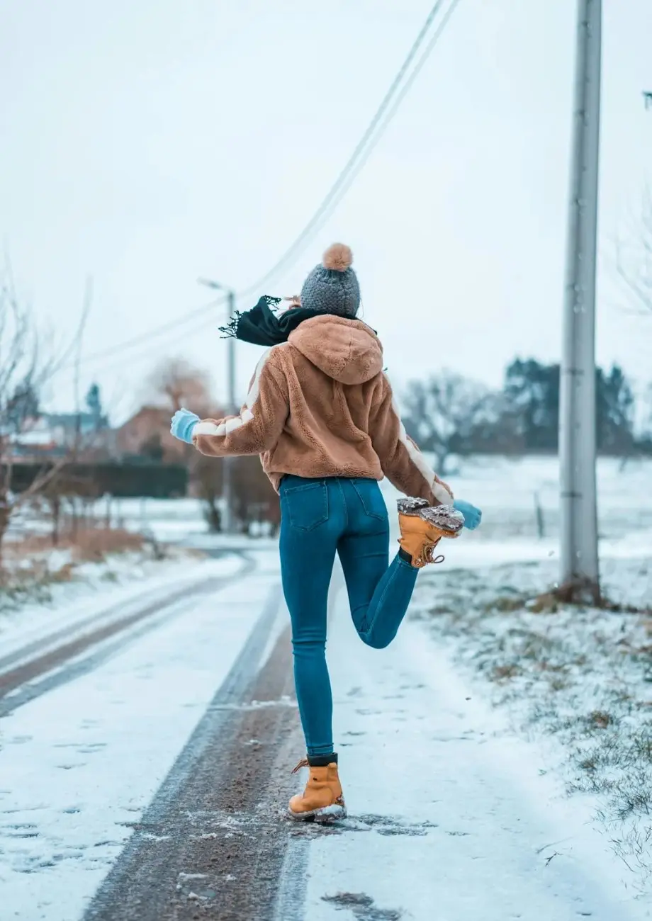 Person wearing Flying Monkey jeans fit during winter walk on a snowy road, showcasing stylish comfort and flexibility in cold weather.