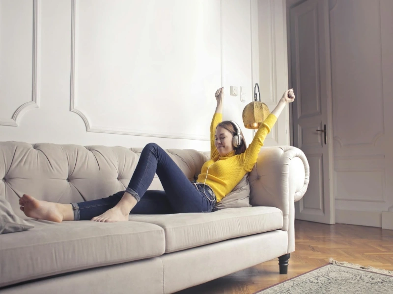 Woman relaxing on a couch wearing stylish cropped flare jeans, showcasing a comfortable and trendy casual look