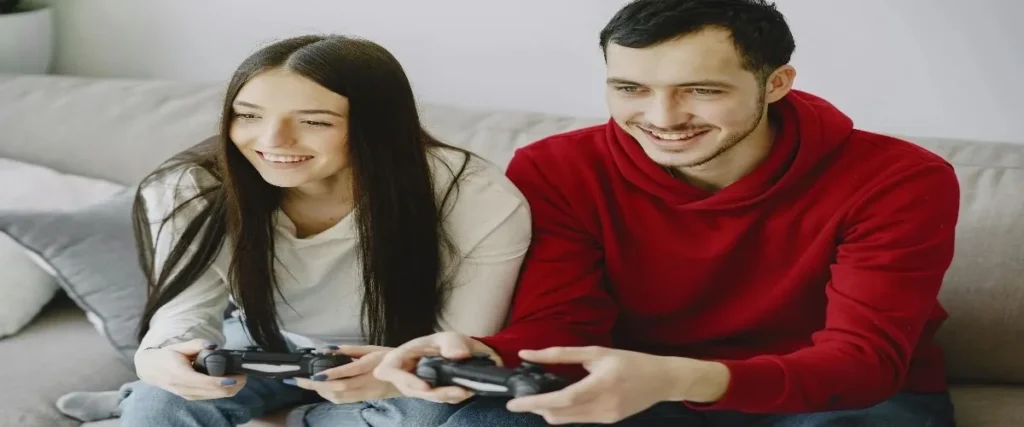 A young man in a red hoodie paired with casual Vervet jeans playing video games, showcasing a relaxed and trendy style perfect for casual hangouts.