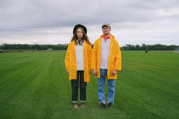 A stylish duo wearing yellow raincoats with Judy Blue capris and jeans, showcasing a perfect summer outfit choice for casual outdoor wear.