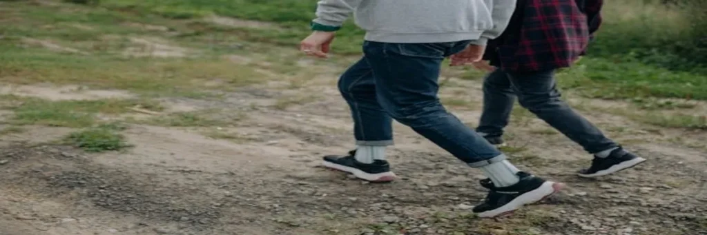 Two people walking outdoors wearing slip-on sneakers paired with rolled-up skinny jeans, showcasing a comfortable and casual look for effortless style and everyday wear."