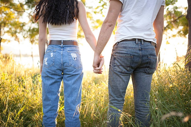 A couple standing in a field, showcasing different types of boyfriend jeans with relaxed and casual fits.