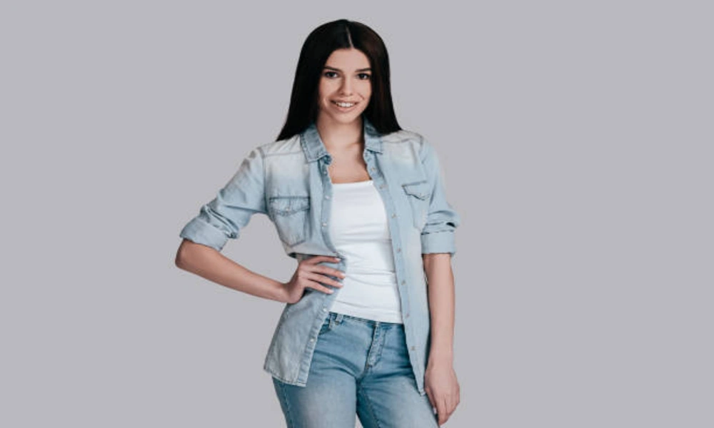 Smiling woman in light denim jacket and jeans, showcasing the stylish and versatile Risen Jeans look.