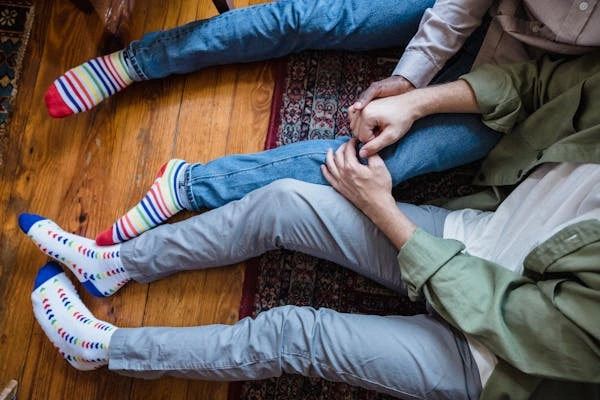 Two people sitting on the floor wearing low-rise denim jeans, showcasing different styles and colorful socks, highlighting the versatility of low-rise jeans for various outfit types.