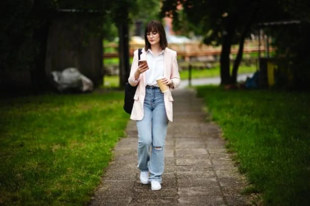 Stylish young woman showcasing a casual chic look with blue jeans, a fitted t-shirt, and sneakers, perfect for a relaxed yet fashionable street style